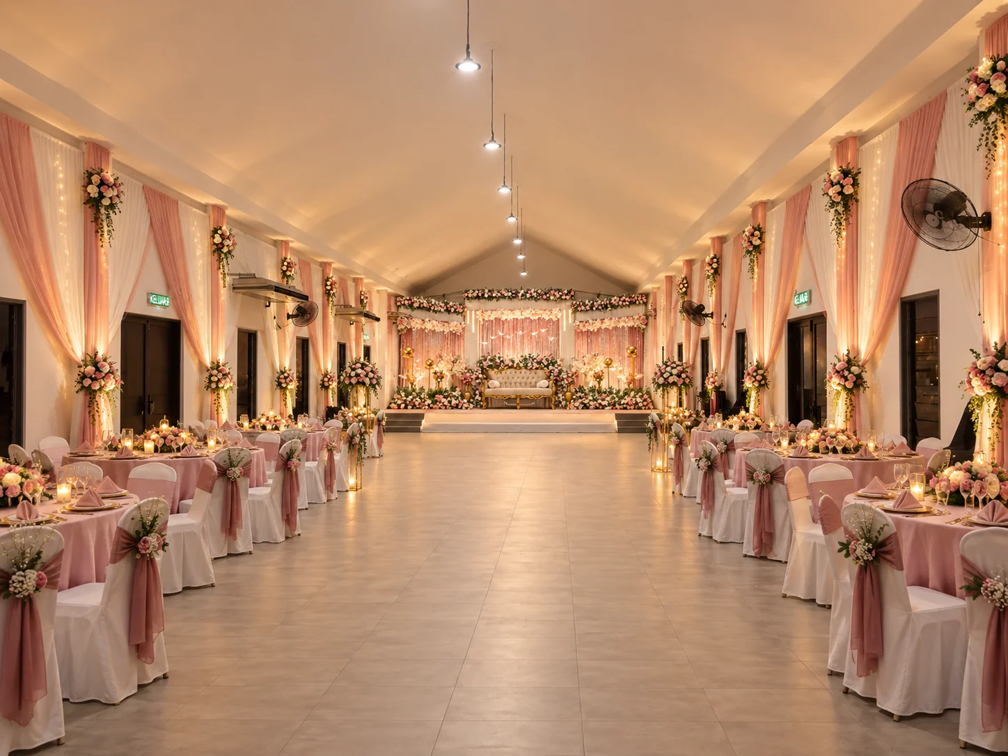 Wedding reception hall with blush draping, floral stage, and dining tables